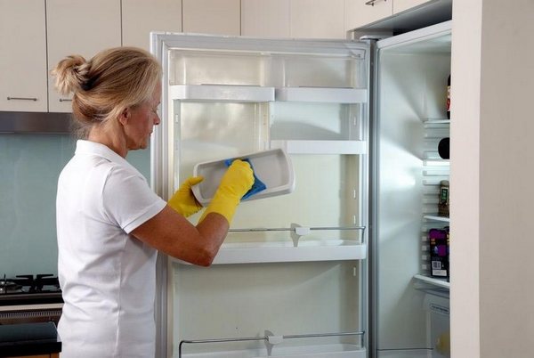 Процес на почистване Жена измива хладилник
